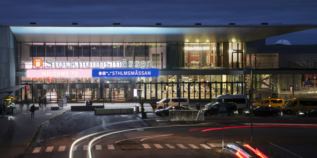 Hållbarhet 6 Stockholmsmässans huvudentré upplyst på kvällen med bilar och människor utanför.