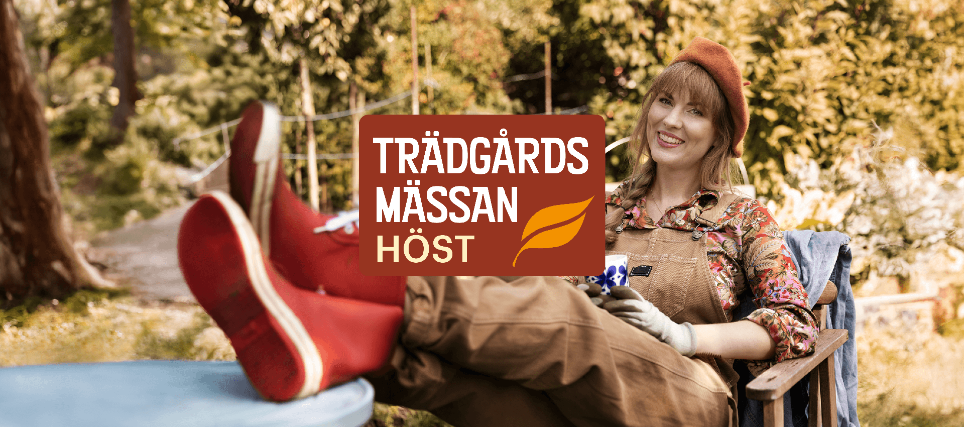 A person is sitting relaxed in a garden with legs elevated, wearing red boots and an orange beret. The person is holding a cup and wearing gardening gloves. In the background, green plants and trees are visible. The text on the image reads "TRÄDGÅRDS MÄSSAN HÖST" with an orange leaf symbol.