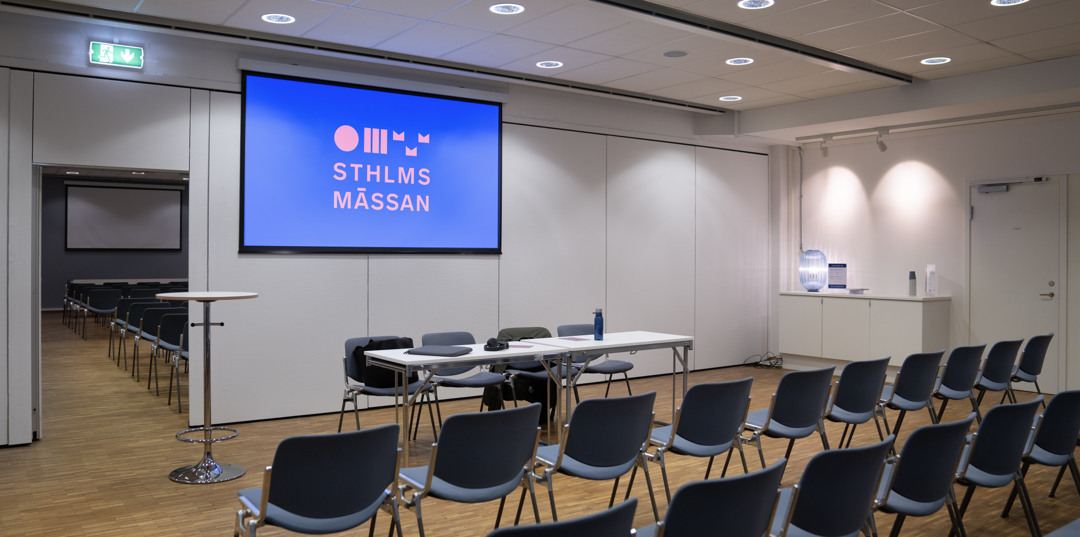 Konferensrum med duk, stolsrader och panelbord, redo för föreläsning på Stockholmsmässan.