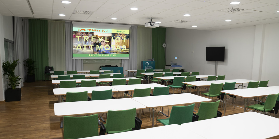 Konferensrum K16 med gröna stolar, redo för presentation eller möte