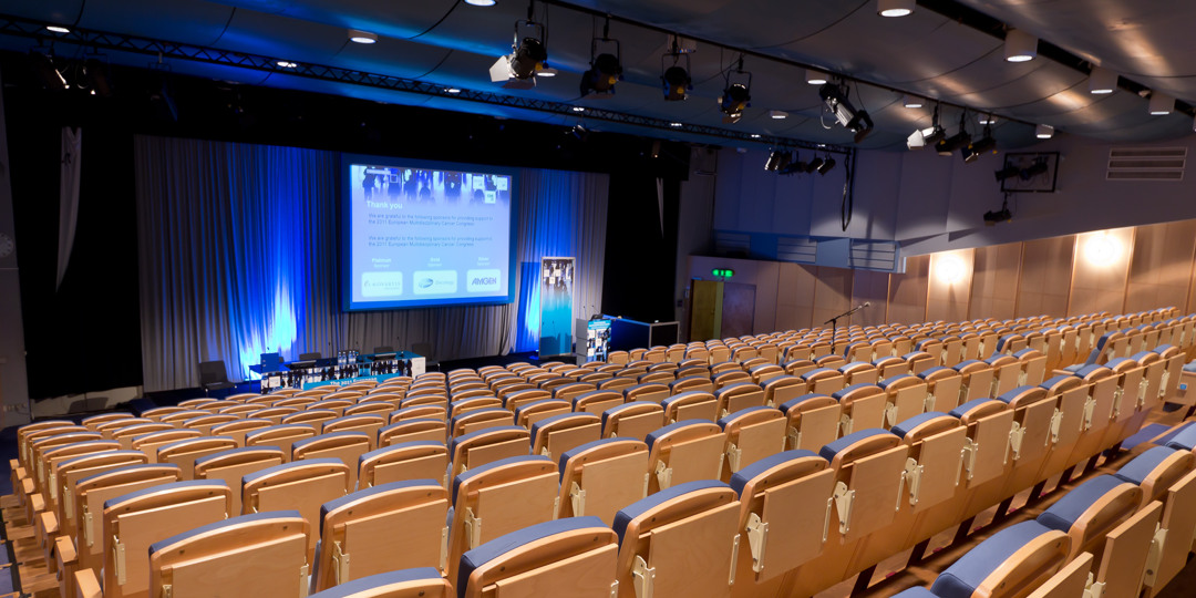 Ljus, modern hörsal med scen och presentationsbild, redo för konferens eller föreläsning.