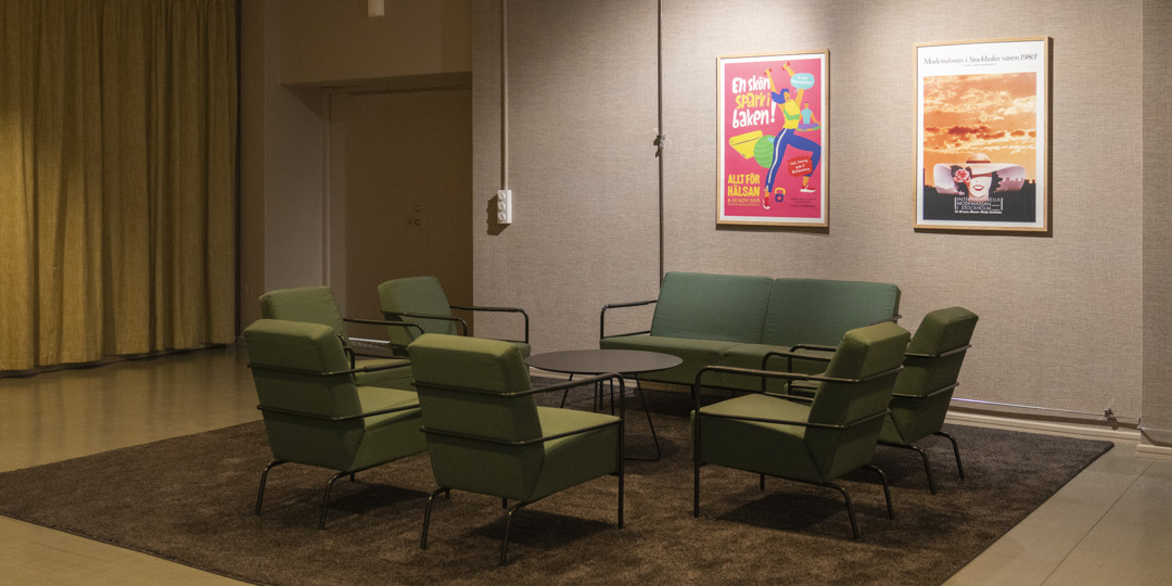 K21-Foaje-stockholmsmässan-1080x540px K21-foajén med grön sittgrupp med fåtöljer och soffa i loungeområde med affischer på väggen.