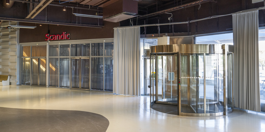 T-entré_stockholmsmässan-1080x540px.jpg Entré med glasdörrar och snurrdörr, intill hotell Scandic Talk inne på Stockholmsmässan.