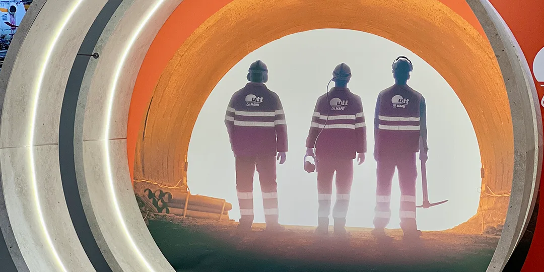 Utställningsportal med bild av tre tunnelarbetare upplysta bakifrån, stående i en tunnel under World Tunnel Congress på Stockholmsmässan.