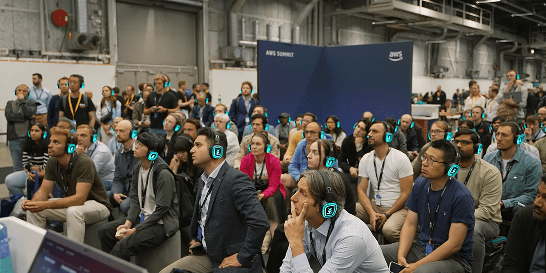 Deltagare med hörlurar lyssnar på föreläsning under AWS Summit Stockholm.