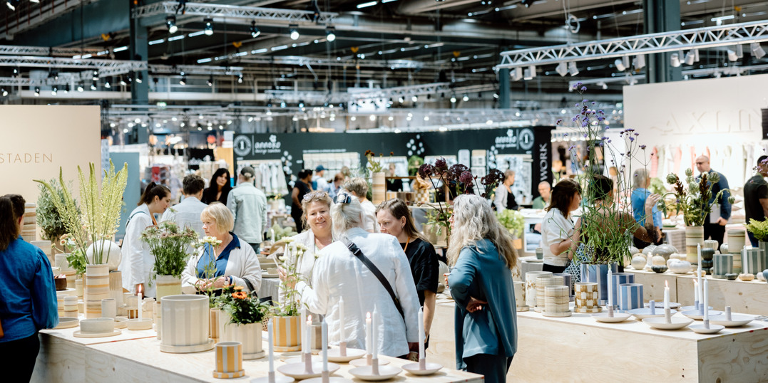 Visitors exploring interior products and plants in a busy exhibition hall at Stockholmsmässan.