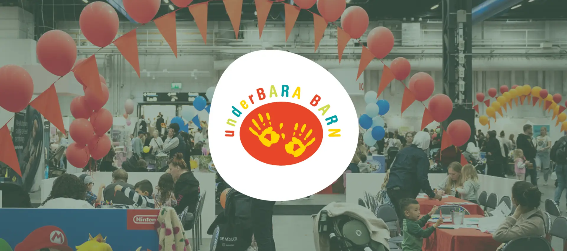 n färgstark mässmiljö med ballonger och vimplar där besökare samlas runt aktivitetsbord, med UnderBARA BARN‑logotypen centrerad i bilden.