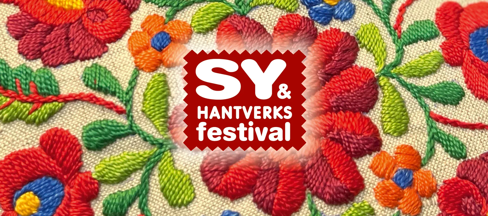 Broderad tygbakgrund med färgstarka blommor i rött, grönt, blått och orange, där en röd logotyp i mitten visar texten ”SY & Hantverksfestival