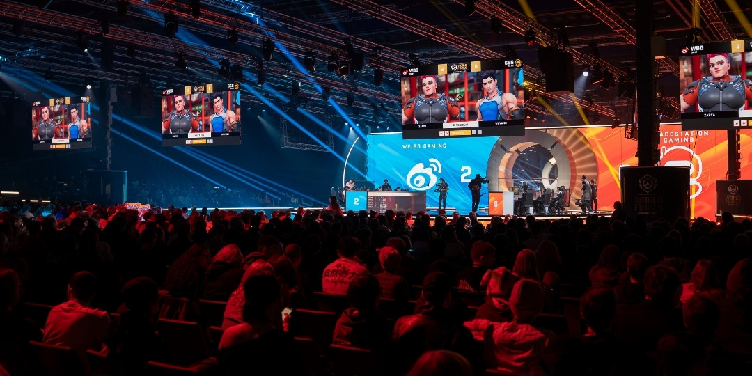 Besökare i eventhall med stora skärmar under ett esportevent.