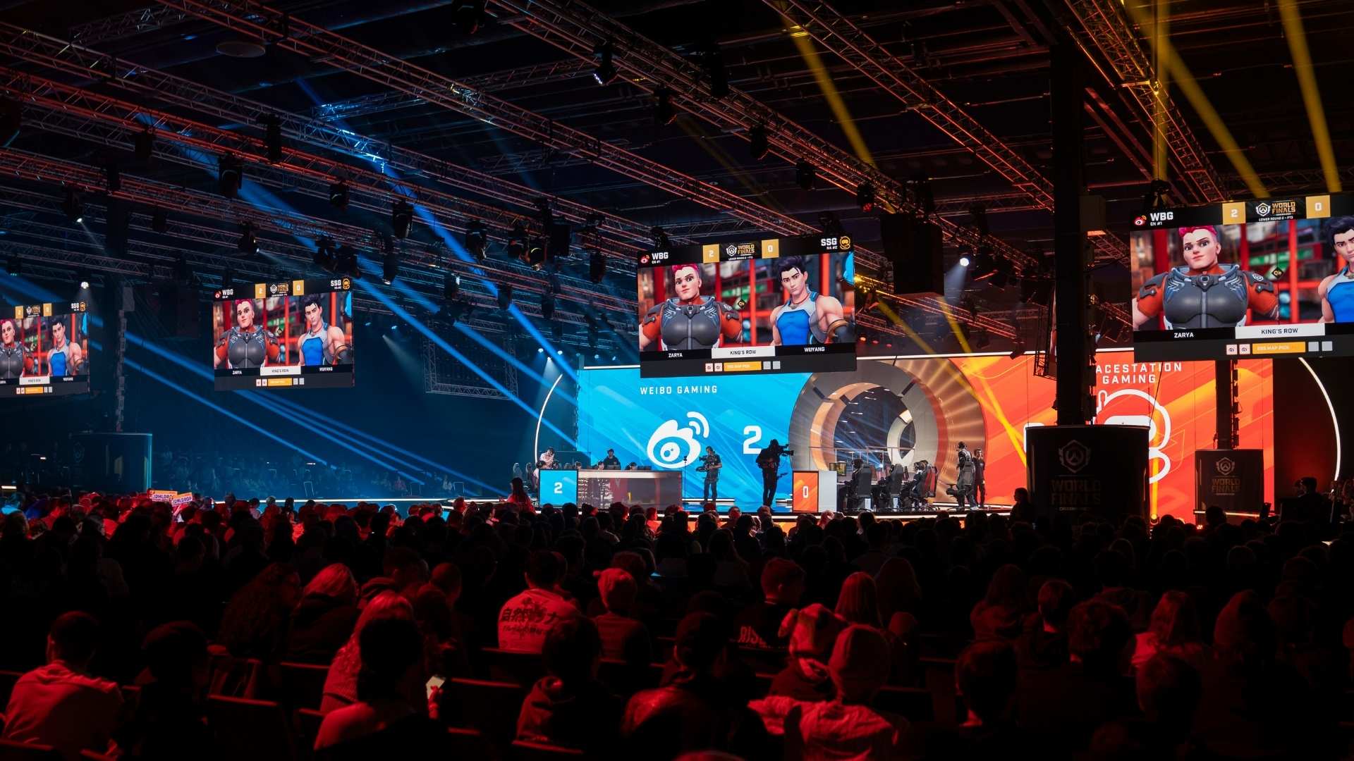 Visitors in an event hall with large screens during an esports event.