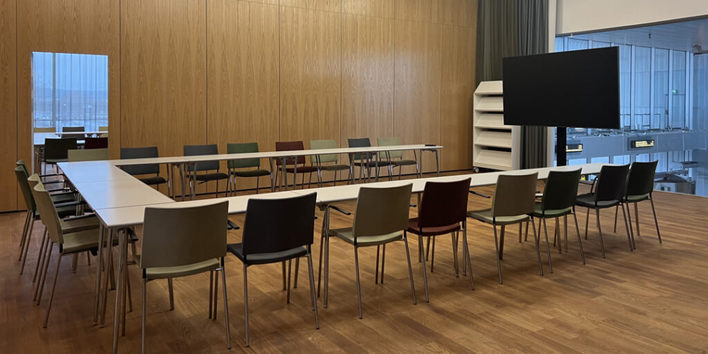 Ett konferensrum med ett bord och stolar uppställda i U-form.